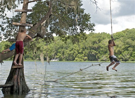 Boys swing into a river during a hot day in Florida.