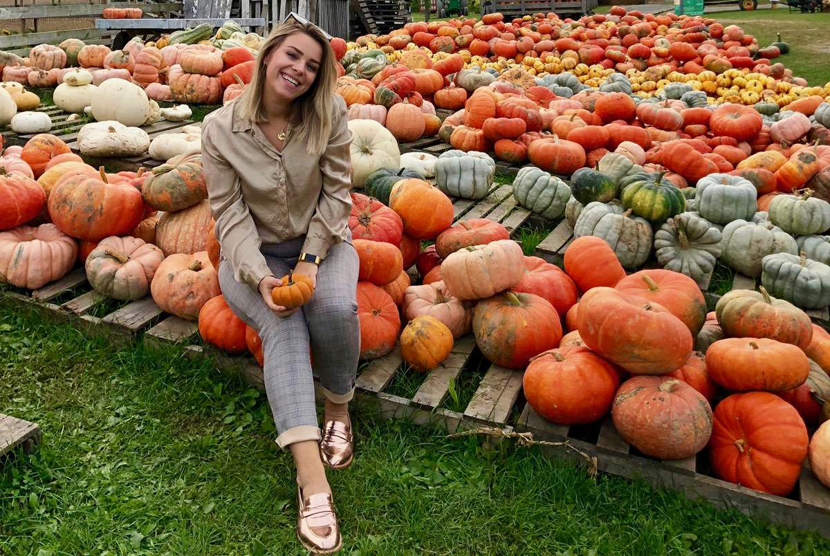 Girl wearing thrifted outfit, posing on a pumpkin field.