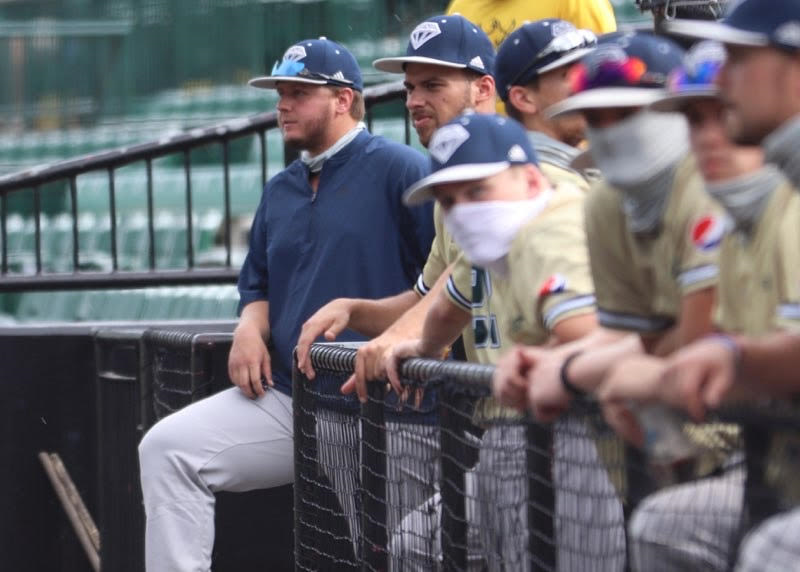 Baseball players line the edge of a dugout.